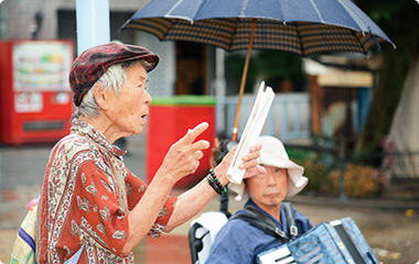 歌集を片手に声高らかに歌う