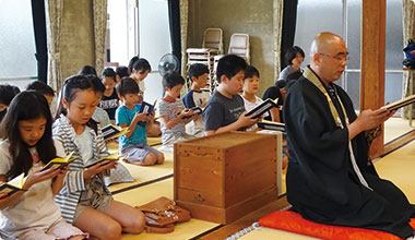寳樹寺の本堂で住職と一緒に日常勤行を唱える子どもたち
